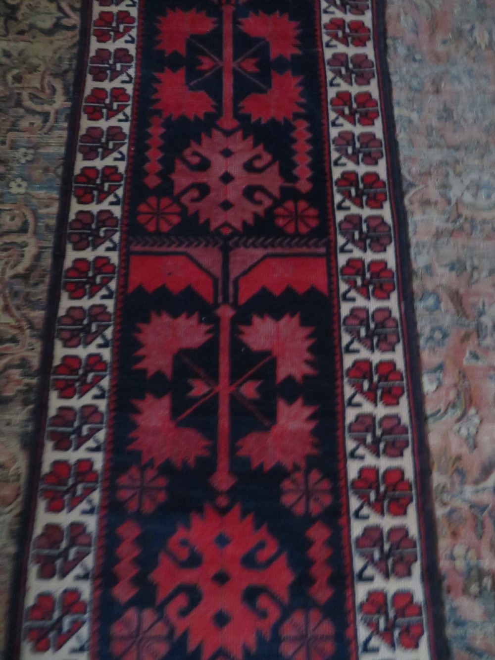 A long, narrow hand-knotted Turkish Yagjibedir runner rug featuring geometric tribal motifs in deep red against a dark navy blue background with a patterned ivory border. View XIII