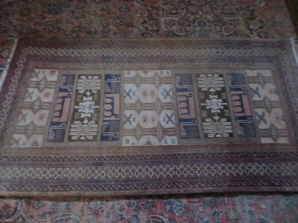 A hand-knotted Afghan wool rug featuring panelled sections with stylized animal motifs and geometric borders in terracotta, beige, brown, and navy blue hues. View IV