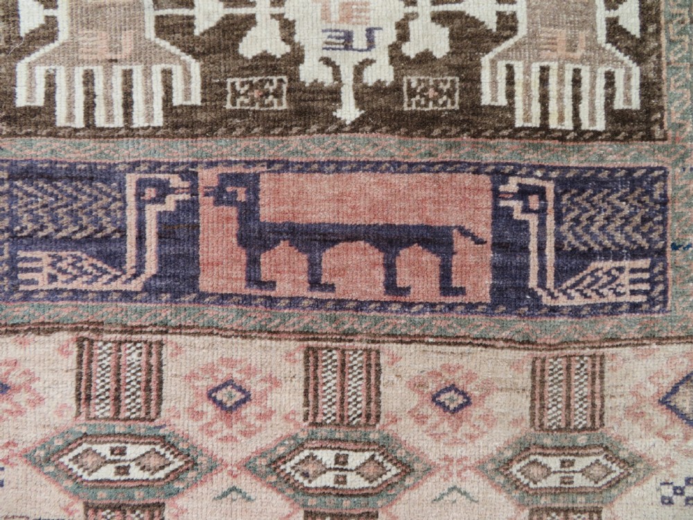 A hand-knotted Afghan wool rug featuring panelled sections with stylized animal motifs and geometric borders in terracotta, beige, brown, and navy blue hues. View V