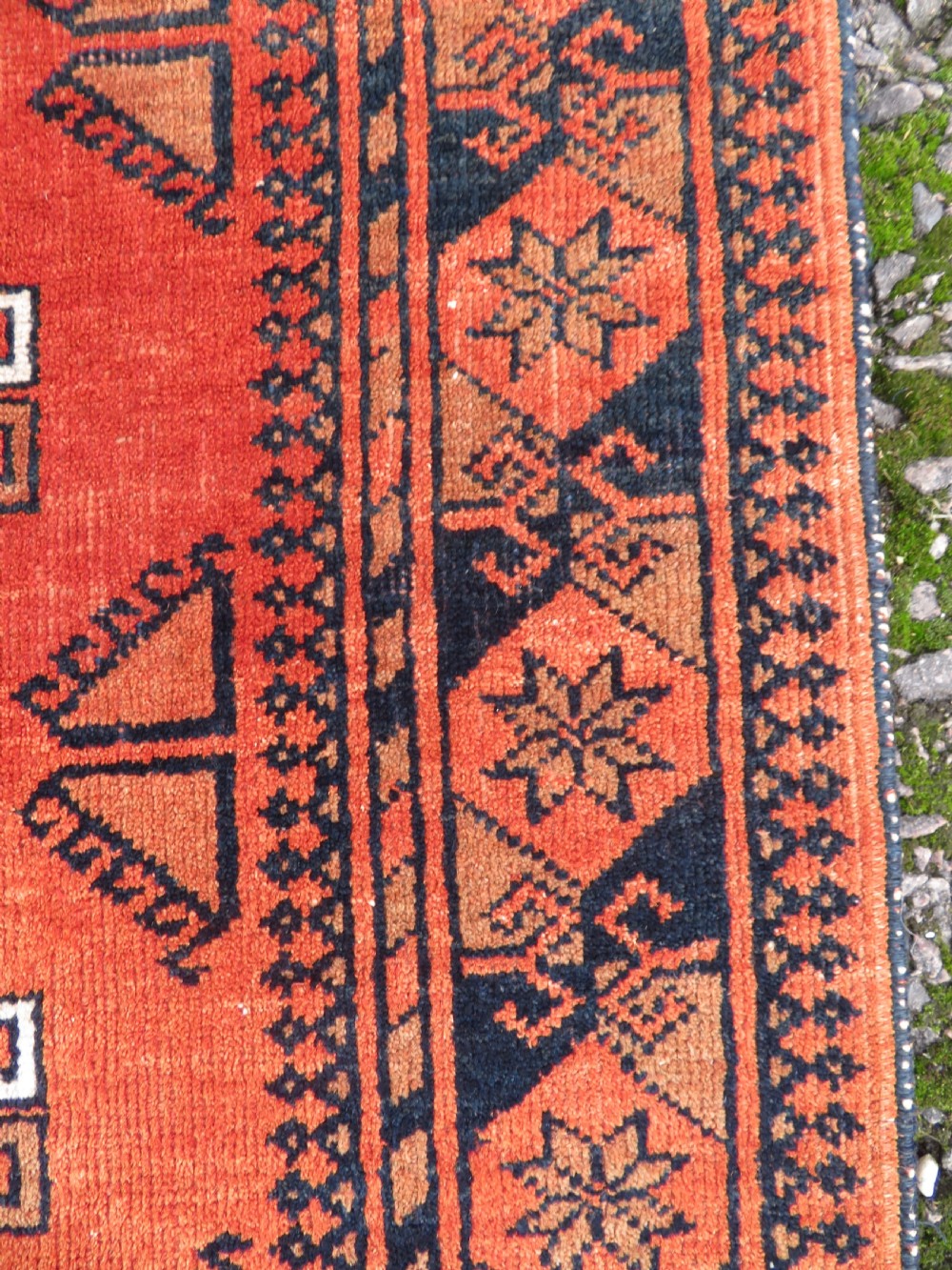 A hand-knotted Afghan wool rug featuring a rust-red field decorated with four diamond latch-hook medallions and geometric borders. View VII