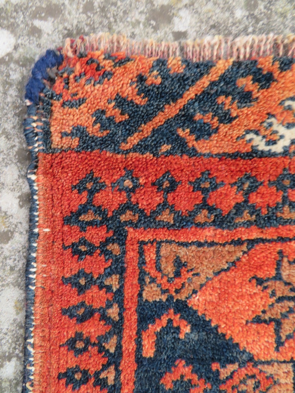 A hand-knotted Afghan wool rug featuring a rust-red field decorated with four diamond latch-hook medallions and geometric borders. View X