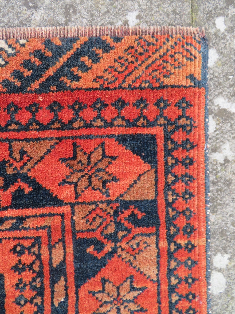 A hand-knotted Afghan wool rug featuring a rust-red field decorated with four diamond latch-hook medallions and geometric borders. View XI
