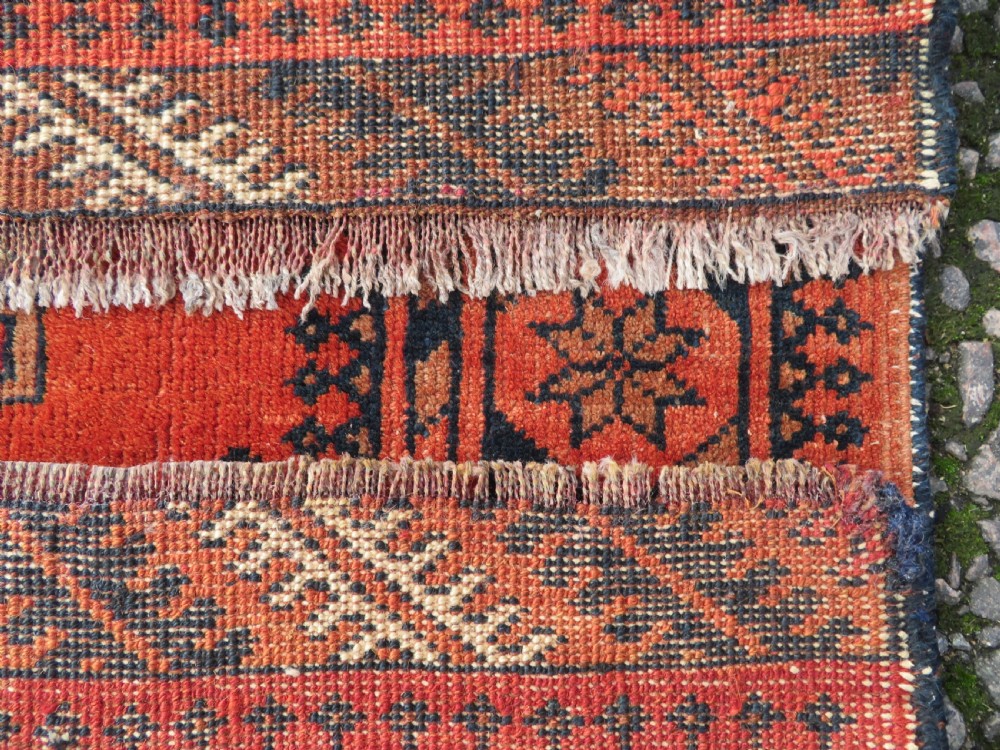 A hand-knotted Afghan wool rug featuring a rust-red field decorated with four diamond latch-hook medallions and geometric borders. View XIII