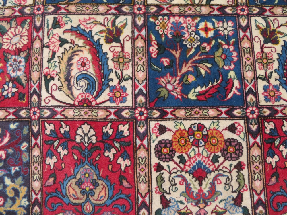 A large hand-knotted Persian Qum carpet with a square compartment panel design featuring floral and boteh motifs in red, blue, and cream enclosed by multi-band borders. View V