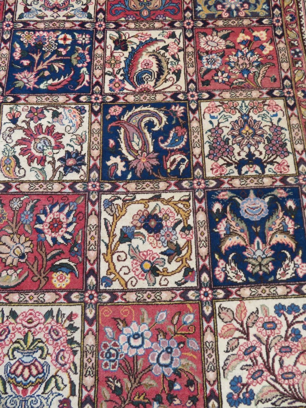 A large hand-knotted Persian Qum carpet with a square compartment panel design featuring floral and boteh motifs in red, blue, and cream enclosed by multi-band borders. View VI