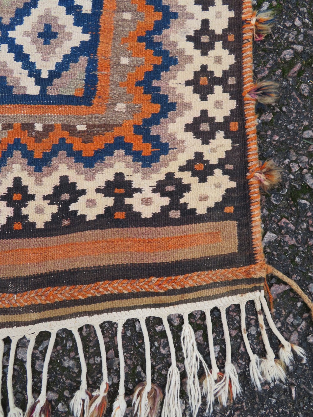 A handwoven Qashqai kilim rug featuring a geometric diamond lattice pattern in terracotta, navy blue, red, and cream with fringed ends. View VI