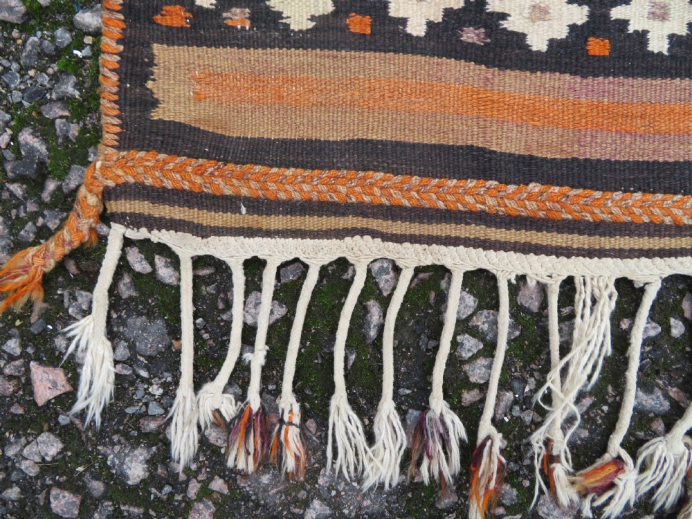 A handwoven Qashqai kilim rug featuring a geometric diamond lattice pattern in terracotta, navy blue, red, and cream with fringed ends. View VII