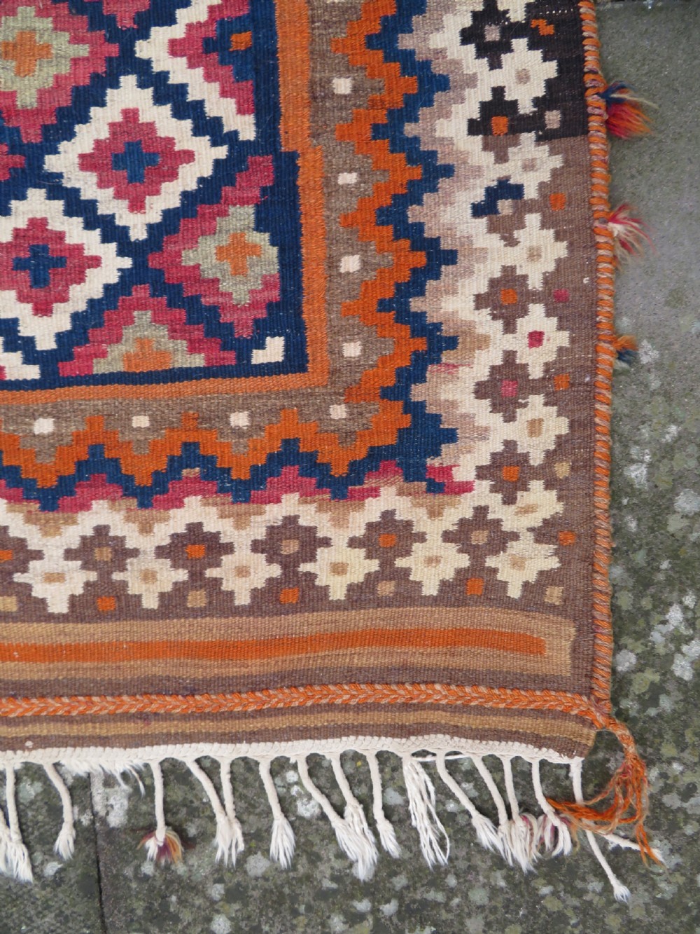 A handwoven Qashqai kilim rug featuring a geometric diamond lattice pattern in terracotta, navy blue, red, and cream with fringed ends. View VIII