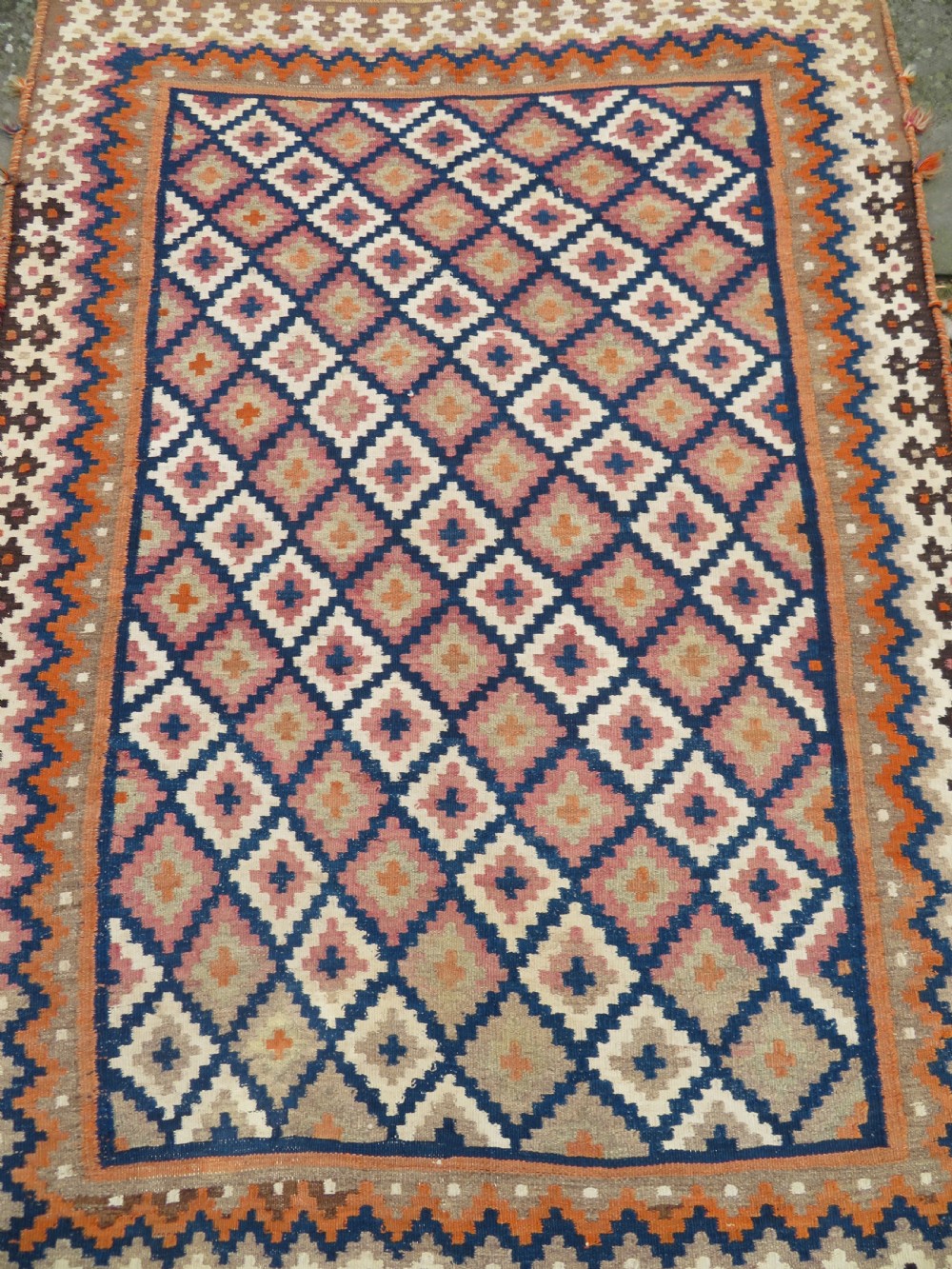 A handwoven Qashqai kilim rug featuring a geometric diamond lattice pattern in terracotta, navy blue, red, and cream with fringed ends. View XIII