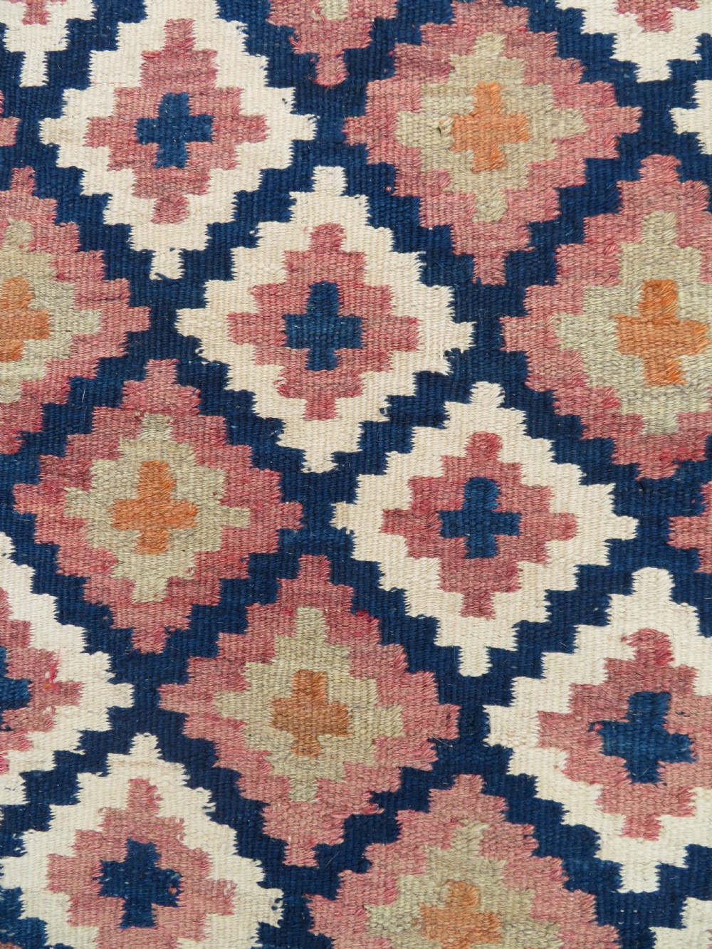 A handwoven Qashqai kilim rug featuring a geometric diamond lattice pattern in terracotta, navy blue, red, and cream with fringed ends. View XVI