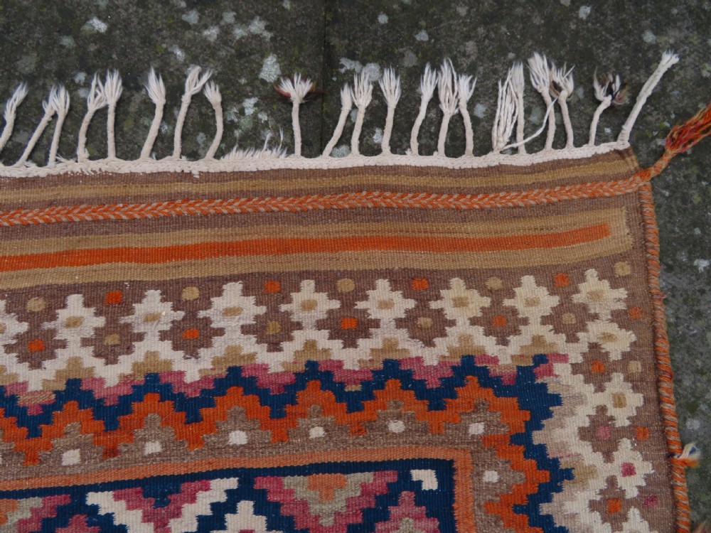 A handwoven Qashqai kilim rug featuring a geometric diamond lattice pattern in terracotta, navy blue, red, and cream with fringed ends. View XVII