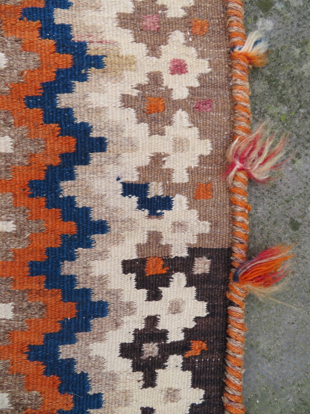 A handwoven Qashqai kilim rug featuring a geometric diamond lattice pattern in terracotta, navy blue, red, and cream with fringed ends. View XIX