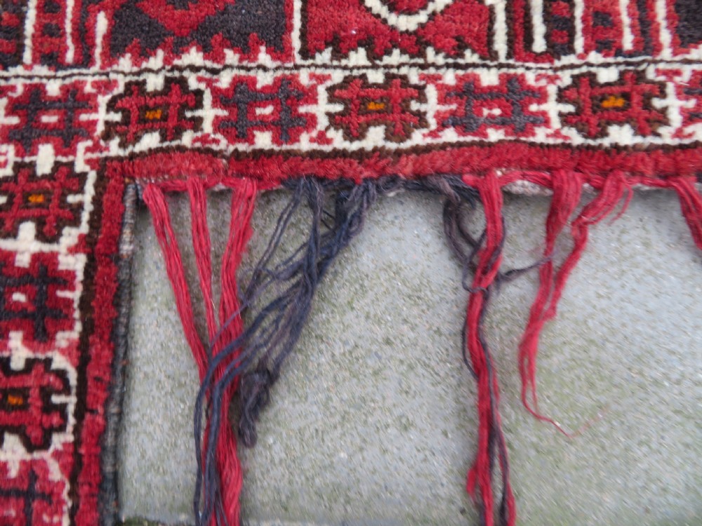A U-shaped hand-woven Yomut Turkmen kapunuk textile in deep red and dark brown wool with geometric patterns and long hanging tassels along the inner arch. View VI
