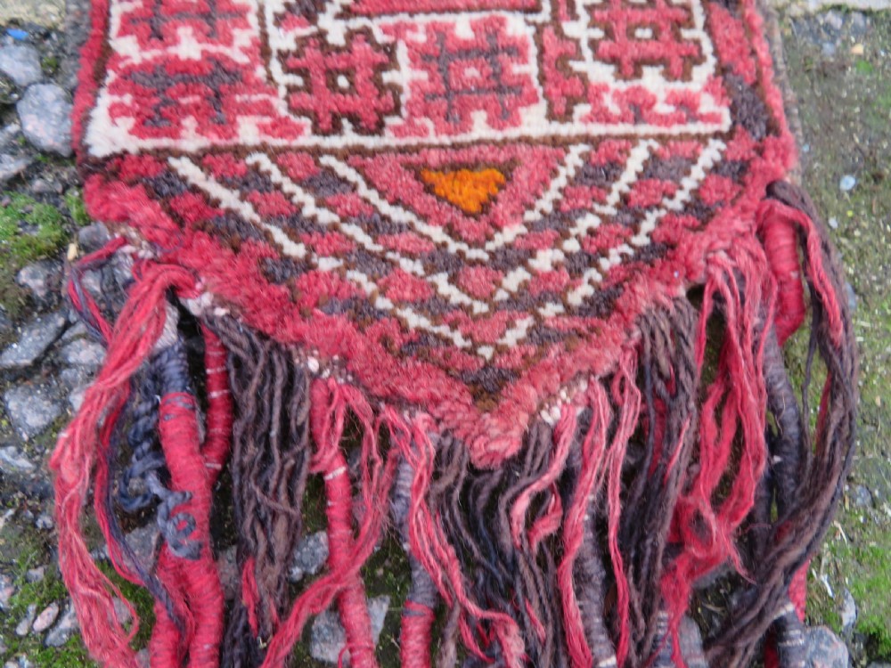 A U-shaped hand-woven Yomut Turkmen kapunuk textile in deep red and dark brown wool with geometric patterns and long hanging tassels along the inner arch. View VIII