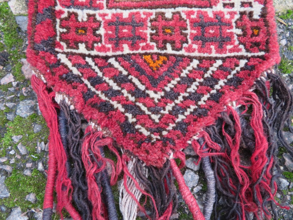 A U-shaped hand-woven Yomut Turkmen kapunuk textile in deep red and dark brown wool with geometric patterns and long hanging tassels along the inner arch. View IX