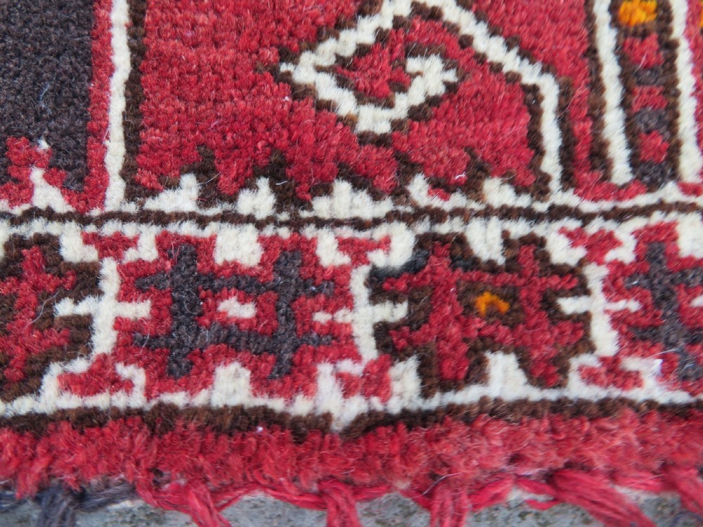 A U-shaped hand-woven Yomut Turkmen kapunuk textile in deep red and dark brown wool with geometric patterns and long hanging tassels along the inner arch. View XI