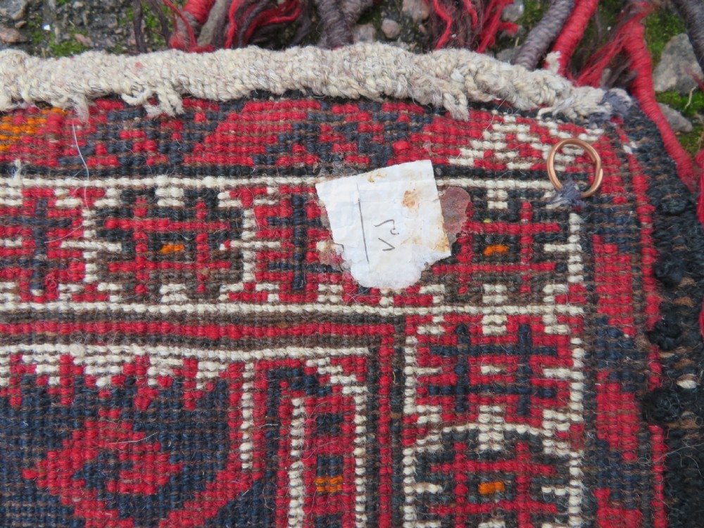 A U-shaped hand-woven Yomut Turkmen kapunuk textile in deep red and dark brown wool with geometric patterns and long hanging tassels along the inner arch. View XIII