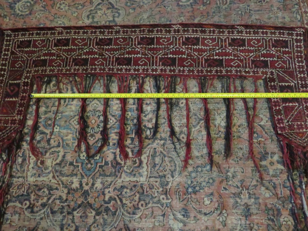 A U-shaped hand-woven Yomut Turkmen kapunuk textile in deep red and dark brown wool with geometric patterns and long hanging tassels along the inner arch. View XIX