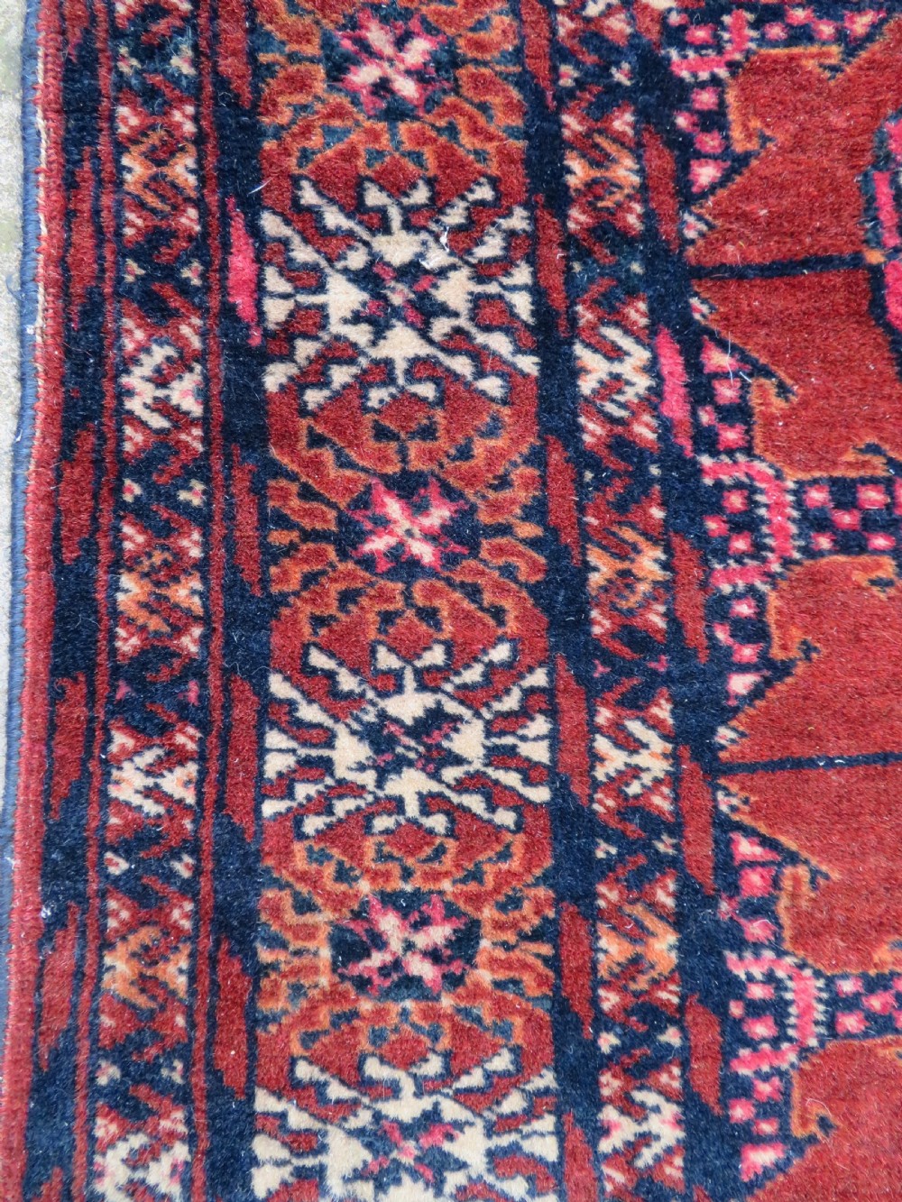 A rectangular hand-knotted Tekke Turkmen wool rug featuring three columns of octagonal gol medallions on a deep red field with geometric borders and fringed ends. View VIII