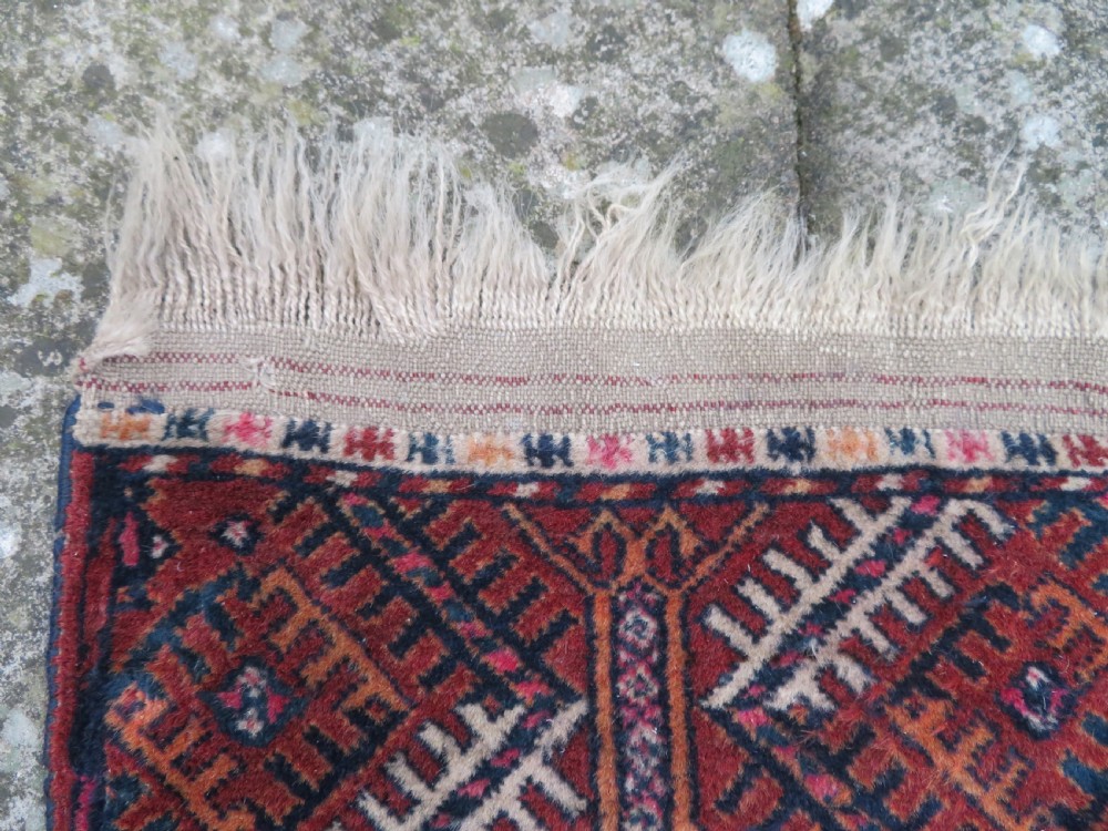 A rectangular hand-knotted Tekke Turkmen wool rug featuring three columns of octagonal gol medallions on a deep red field with geometric borders and fringed ends. View X