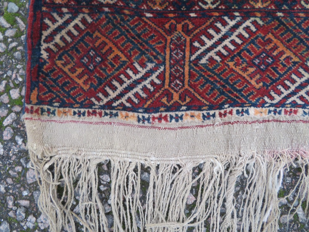 A rectangular hand-knotted Tekke Turkmen wool rug featuring three columns of octagonal gol medallions on a deep red field with geometric borders and fringed ends. View XIII