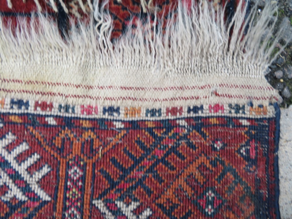 A rectangular hand-knotted Tekke Turkmen wool rug featuring three columns of octagonal gol medallions on a deep red field with geometric borders and fringed ends. View XVI