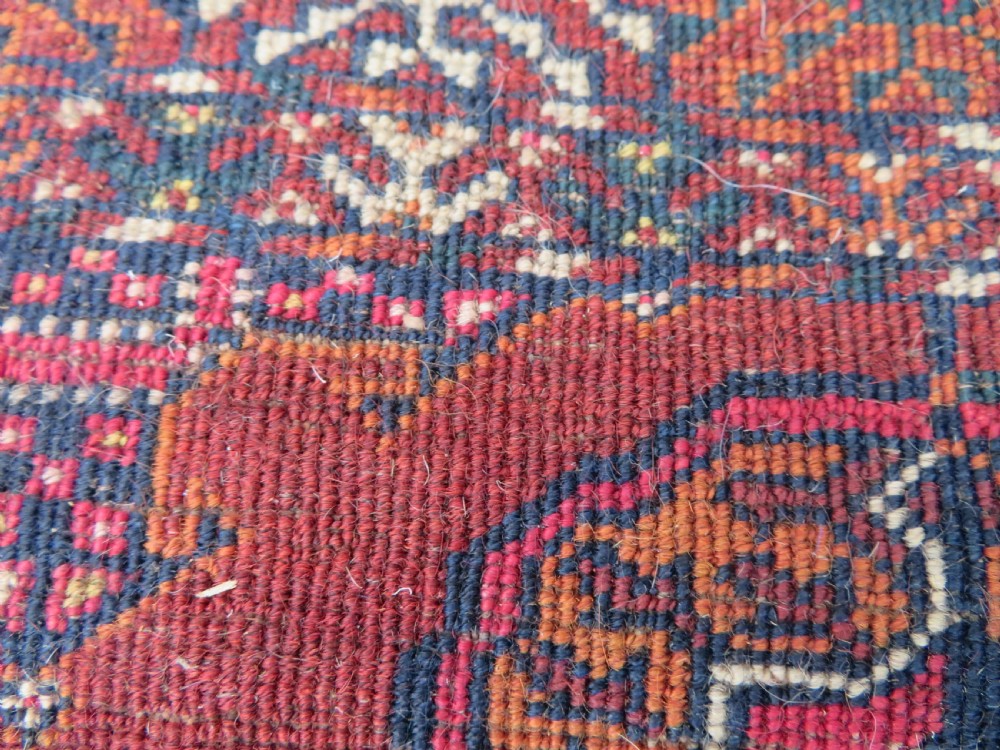 A rectangular hand-knotted Tekke Turkmen wool rug featuring three columns of octagonal gol medallions on a deep red field with geometric borders and fringed ends. View XVII