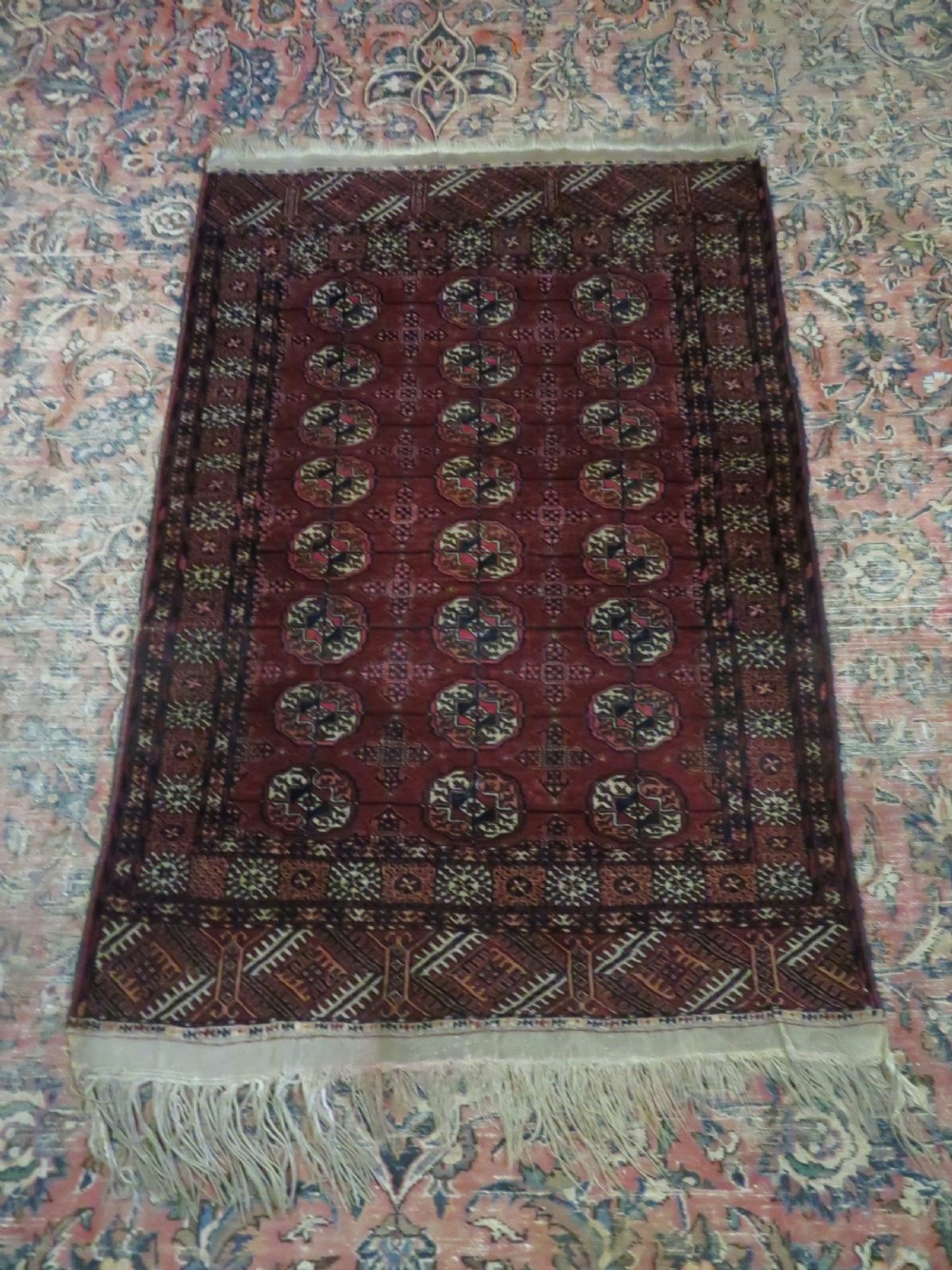 A rectangular hand-knotted Tekke Turkmen wool rug featuring three columns of octagonal gol medallions on a deep red field with geometric borders and fringed ends. View XVIII