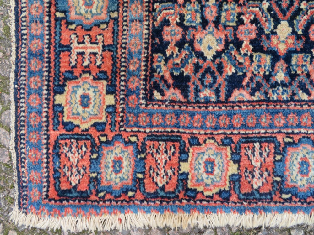 An antique Kurdish Senneh hand-knotted wool rug featuring a central stepped diamond medallion surrounded by detailed repeating motifs in navy blue, terracotta red, and cream. View VIII