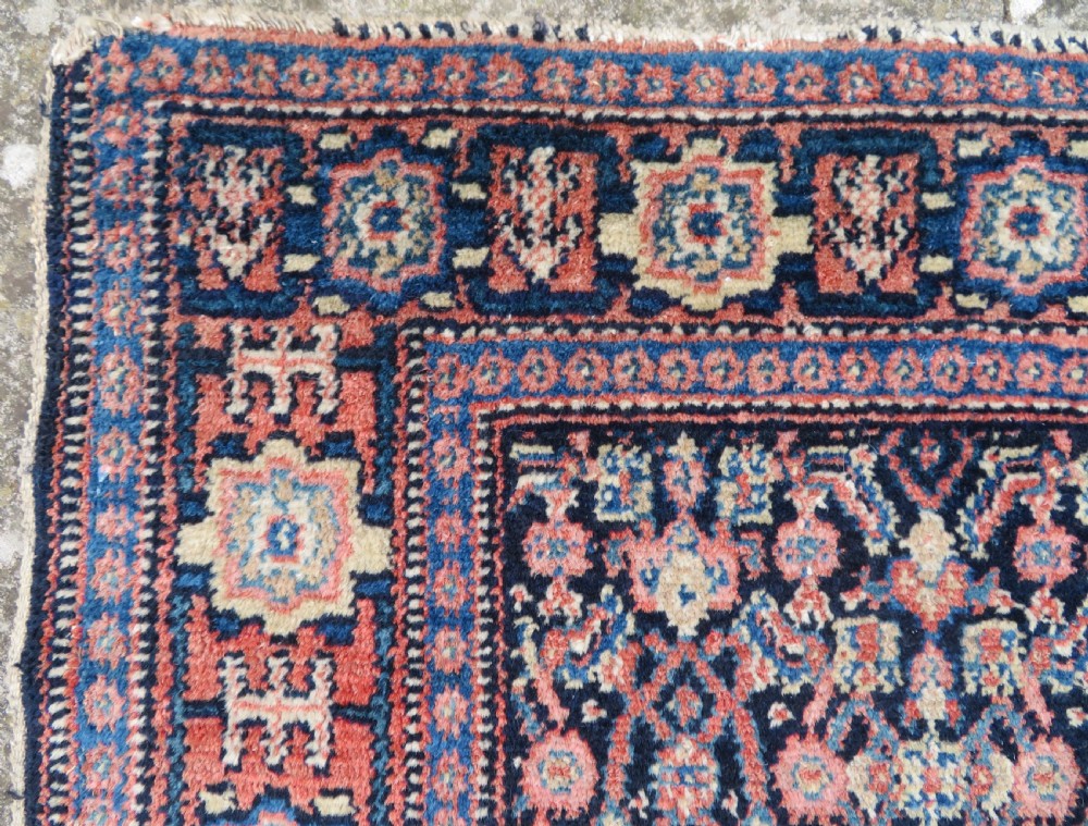 An antique Kurdish Senneh hand-knotted wool rug featuring a central stepped diamond medallion surrounded by detailed repeating motifs in navy blue, terracotta red, and cream. View XI