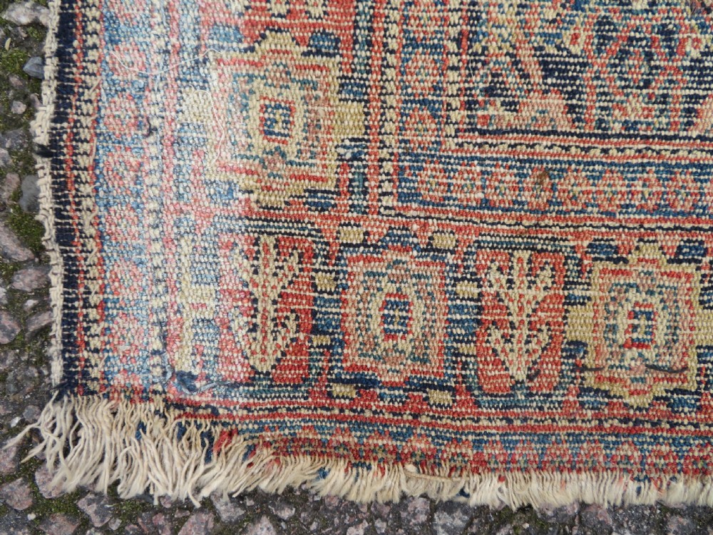 An antique Kurdish Senneh hand-knotted wool rug featuring a central stepped diamond medallion surrounded by detailed repeating motifs in navy blue, terracotta red, and cream. View XV