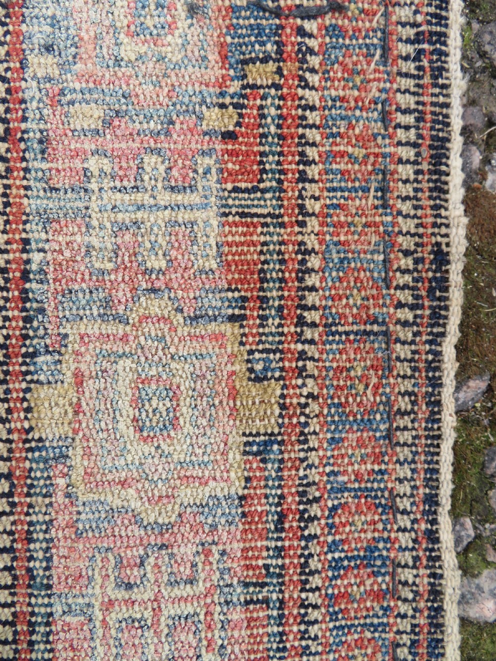 An antique Kurdish Senneh hand-knotted wool rug featuring a central stepped diamond medallion surrounded by detailed repeating motifs in navy blue, terracotta red, and cream. View XVII