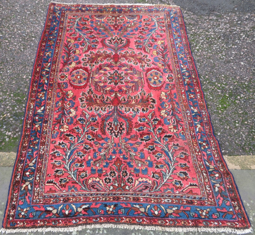An antique Persian Sarouk hand-knotted wool rug featuring a central floral medallion surrounded by intricate floral vine patterns in rose pink, light blue, navy, and ivory hues. View II