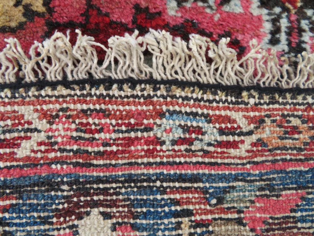 An antique Persian Sarouk hand-knotted wool rug featuring a central floral medallion surrounded by intricate floral vine patterns in rose pink, light blue, navy, and ivory hues. View XX