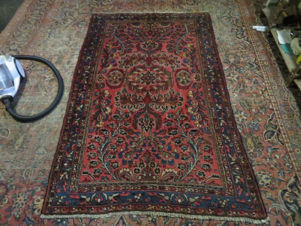 An antique Persian Sarouk hand-knotted wool rug featuring a central floral medallion surrounded by intricate floral vine patterns in rose pink, light blue, navy, and ivory hues. View XXIV