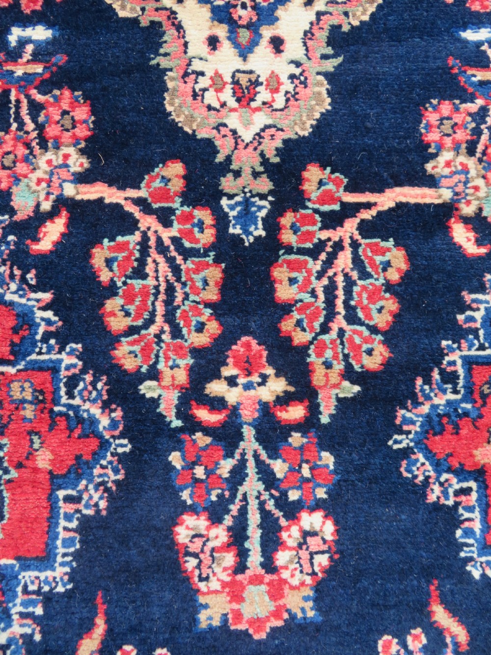 An extra-long antique Persian Sarouk runner rug crafted in wool with navy blue, crimson red, and ivory floral medallion motifs. View III