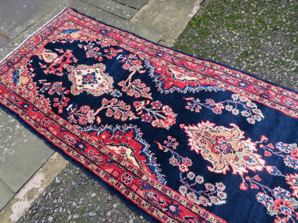 An extra-long antique Persian Sarouk runner rug crafted in wool with navy blue, crimson red, and ivory floral medallion motifs. View XIV