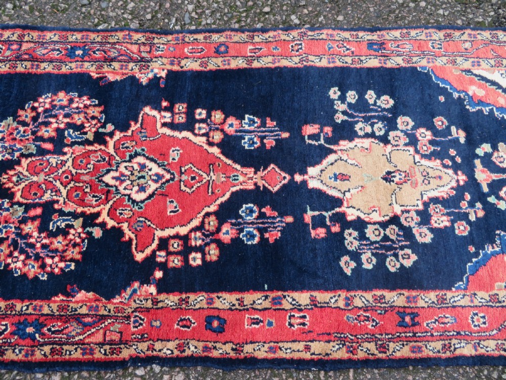 An extra-long antique Persian Sarouk runner rug crafted in wool with navy blue, crimson red, and ivory floral medallion motifs. View XV