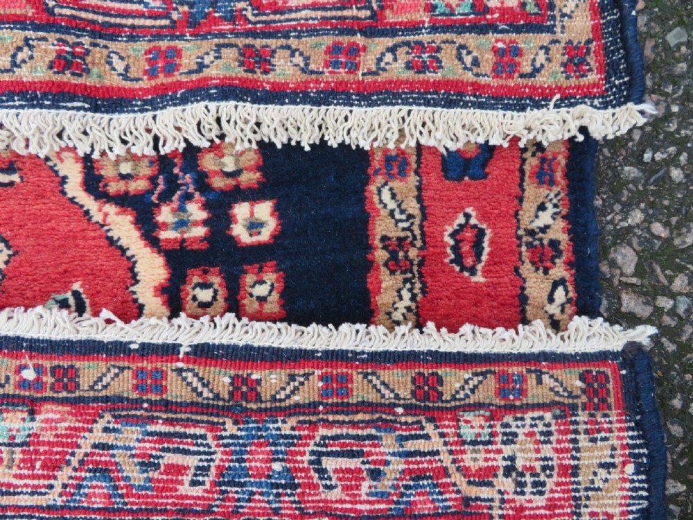 An extra-long antique Persian Sarouk runner rug crafted in wool with navy blue, crimson red, and ivory floral medallion motifs. View XVII