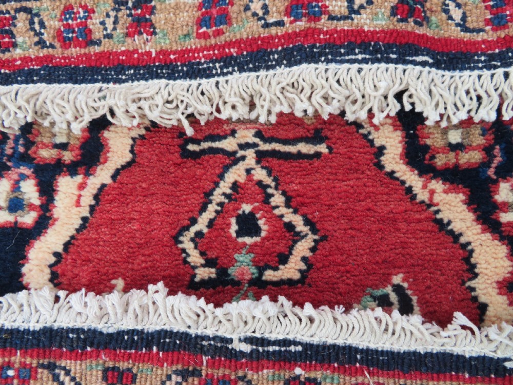 An extra-long antique Persian Sarouk runner rug crafted in wool with navy blue, crimson red, and ivory floral medallion motifs. View XVIII