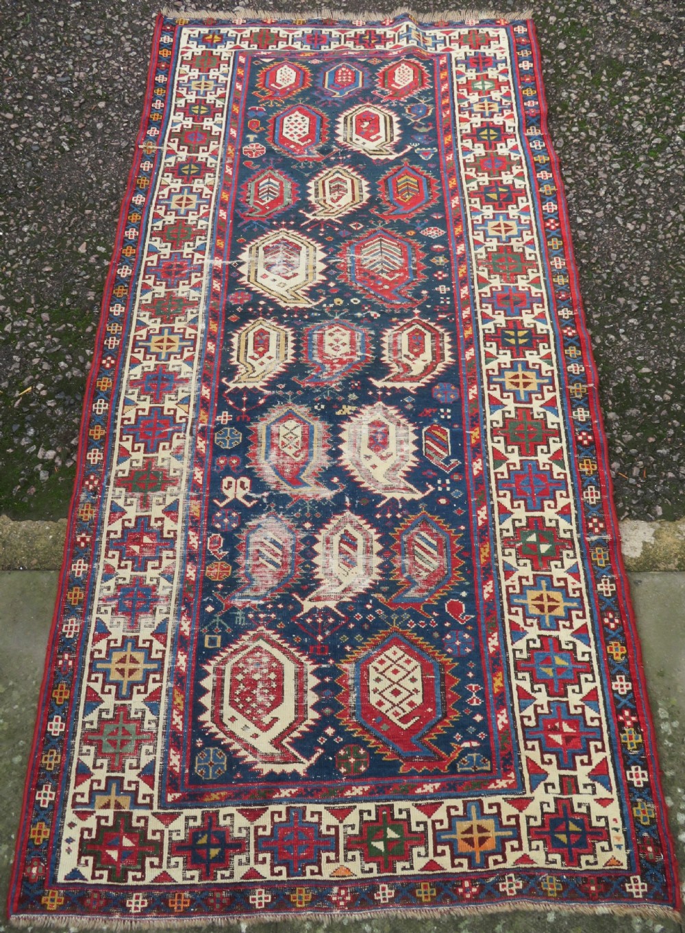 An antique Caucasian Kazak wool runner rug with repeating boteh motifs on a navy blue field framed by geometric multicoloured borders. View II