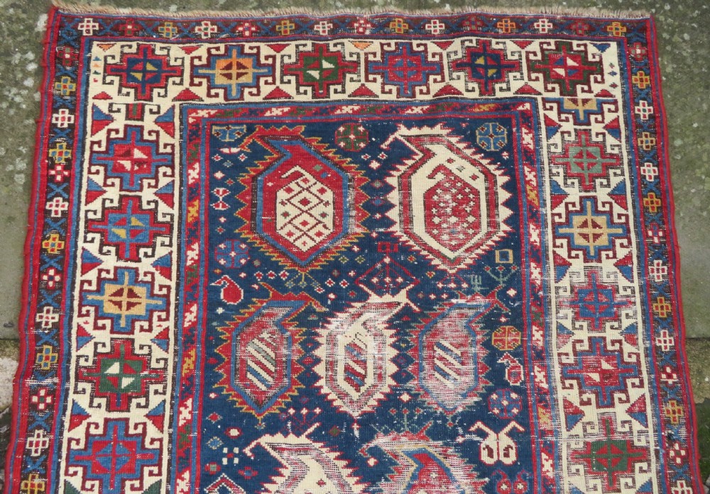 An antique Caucasian Kazak wool runner rug with repeating boteh motifs on a navy blue field framed by geometric multicoloured borders. View V