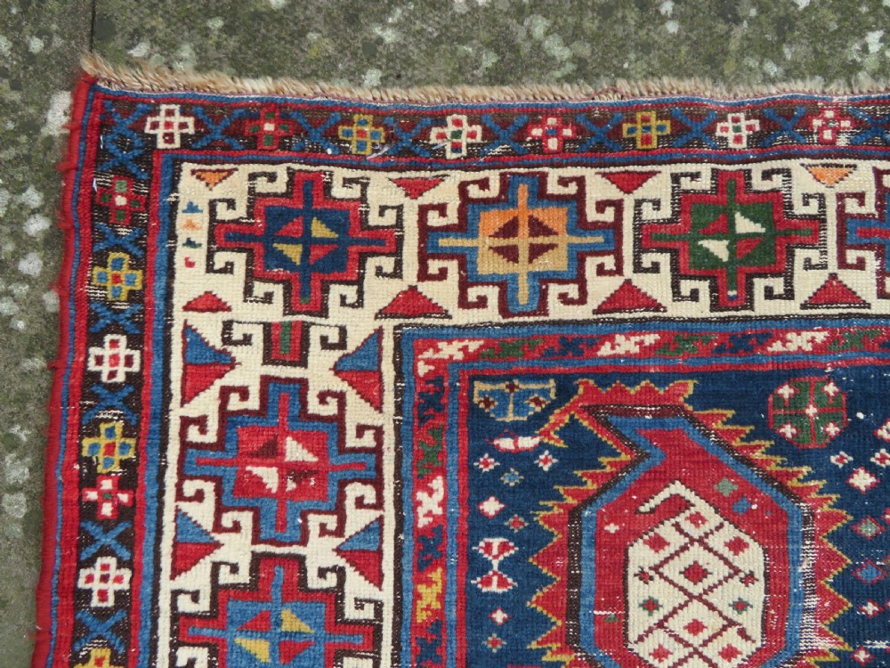 An antique Caucasian Kazak wool runner rug with repeating boteh motifs on a navy blue field framed by geometric multicoloured borders. View VIII