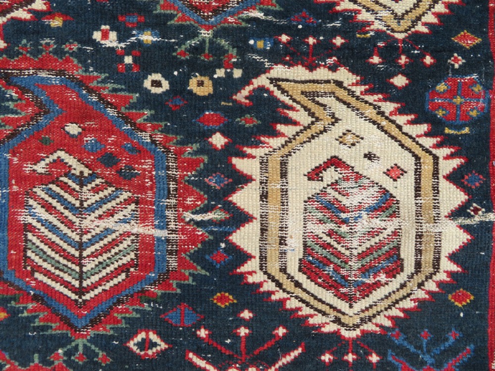 An antique Caucasian Kazak wool runner rug with repeating boteh motifs on a navy blue field framed by geometric multicoloured borders. View XI