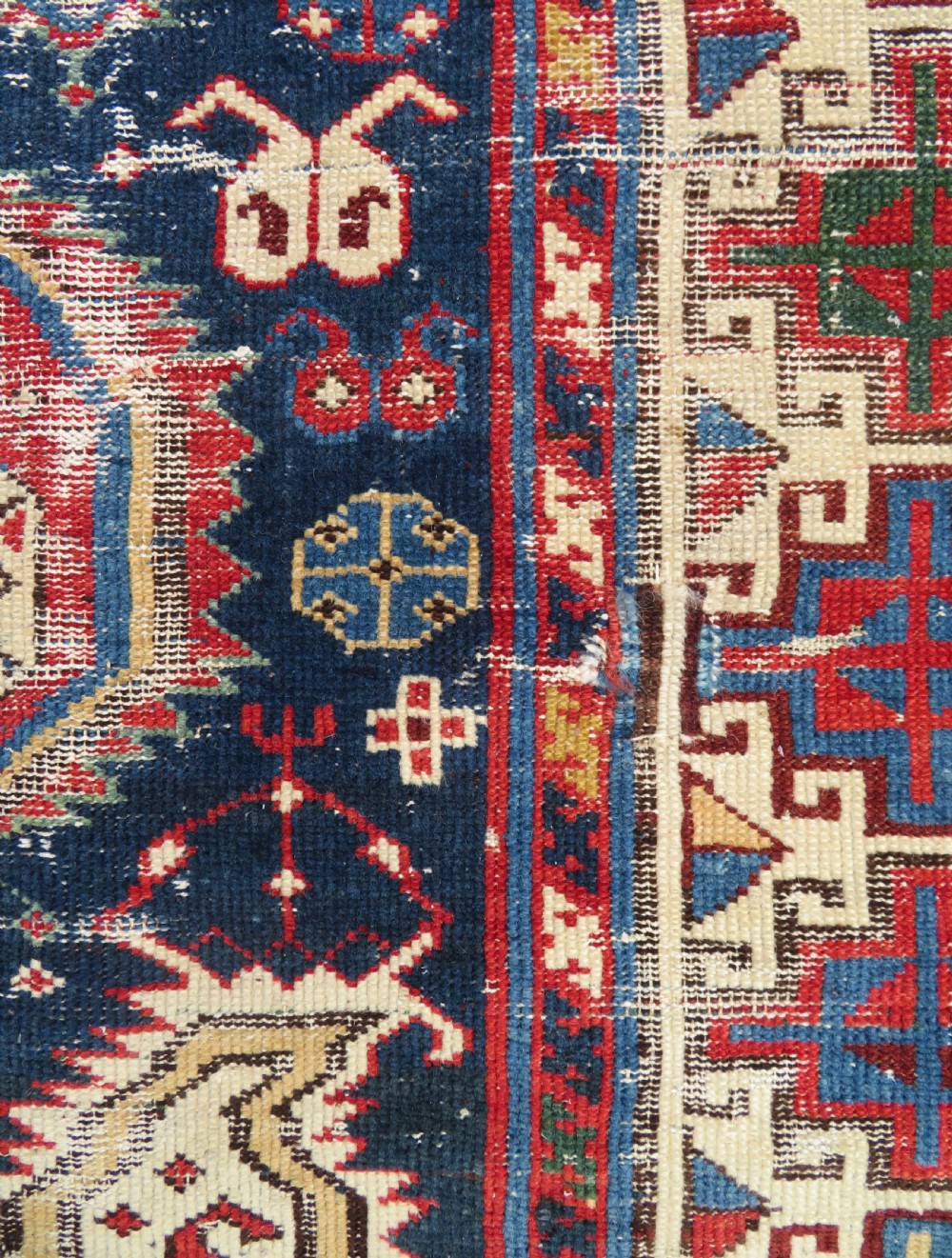 An antique Caucasian Kazak wool runner rug with repeating boteh motifs on a navy blue field framed by geometric multicoloured borders. View XII