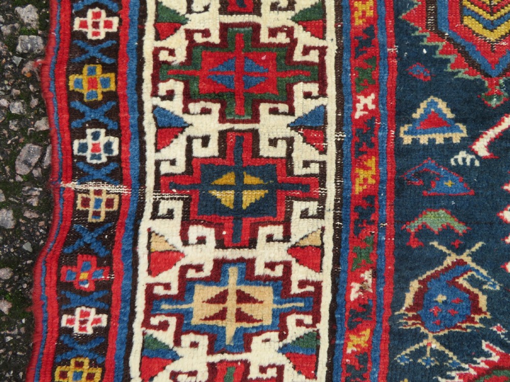 An antique Caucasian Kazak wool runner rug with repeating boteh motifs on a navy blue field framed by geometric multicoloured borders. View XIII