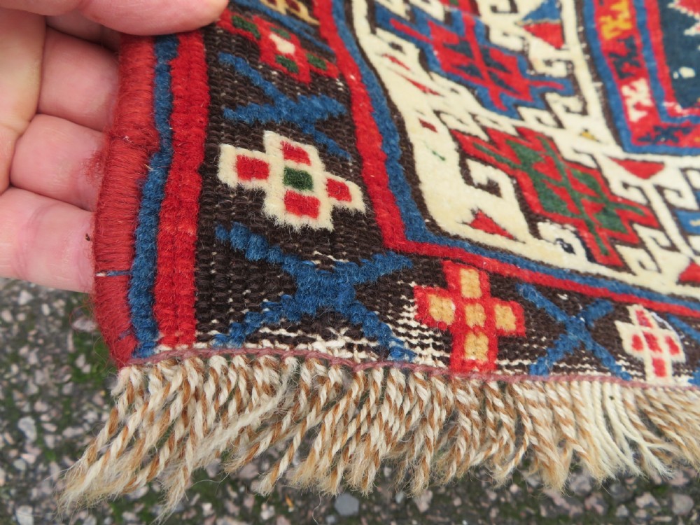 An antique Caucasian Kazak wool runner rug with repeating boteh motifs on a navy blue field framed by geometric multicoloured borders. View XIV