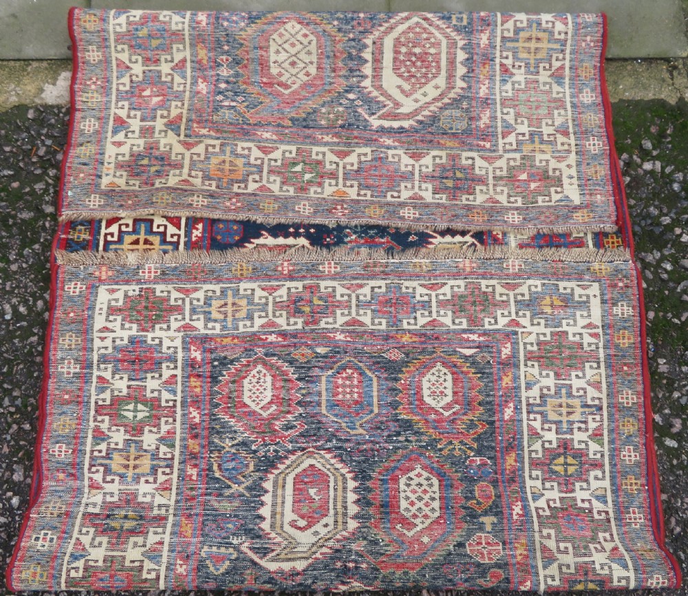 An antique Caucasian Kazak wool runner rug with repeating boteh motifs on a navy blue field framed by geometric multicoloured borders. View XV