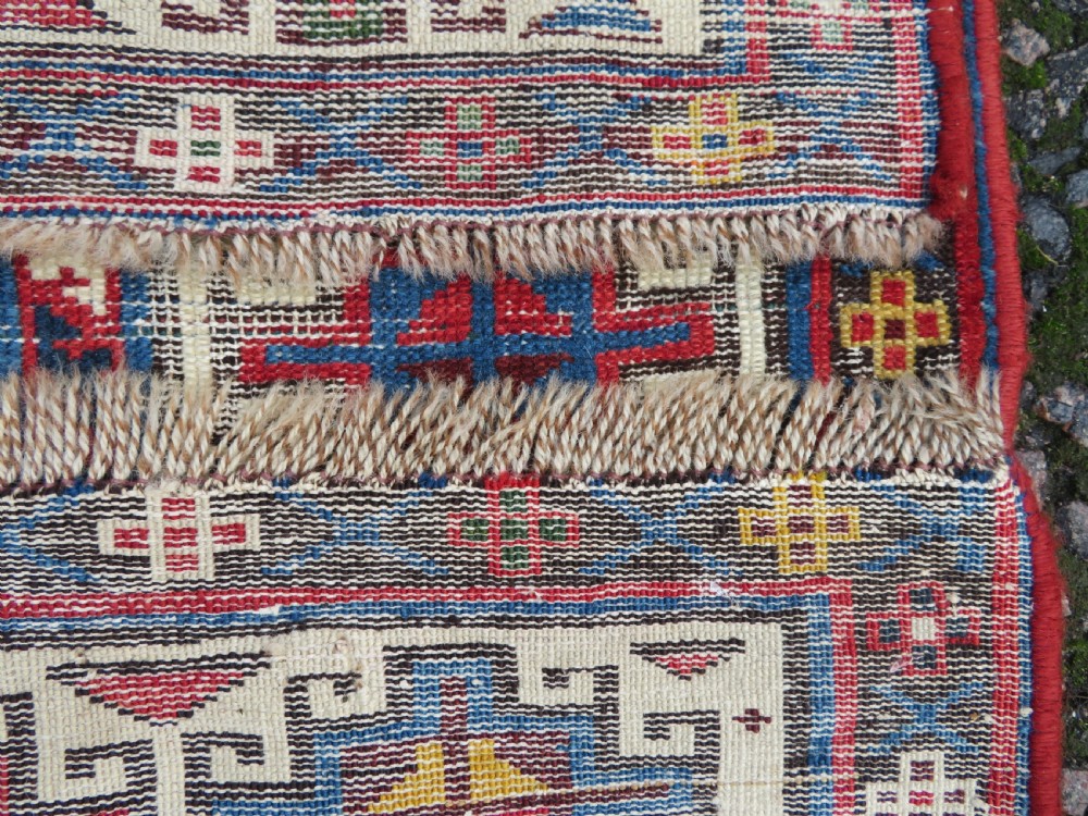 An antique Caucasian Kazak wool runner rug with repeating boteh motifs on a navy blue field framed by geometric multicoloured borders. View XVII