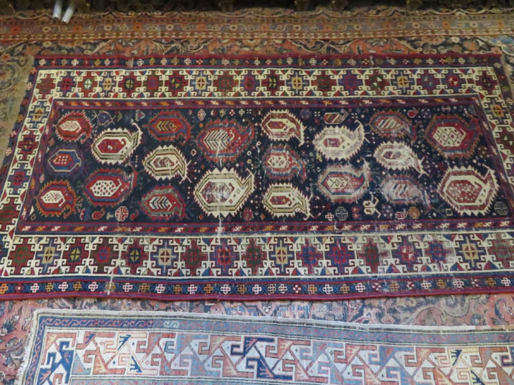 An antique Caucasian Kazak wool runner rug with repeating boteh motifs on a navy blue field framed by geometric multicoloured borders. View XX
